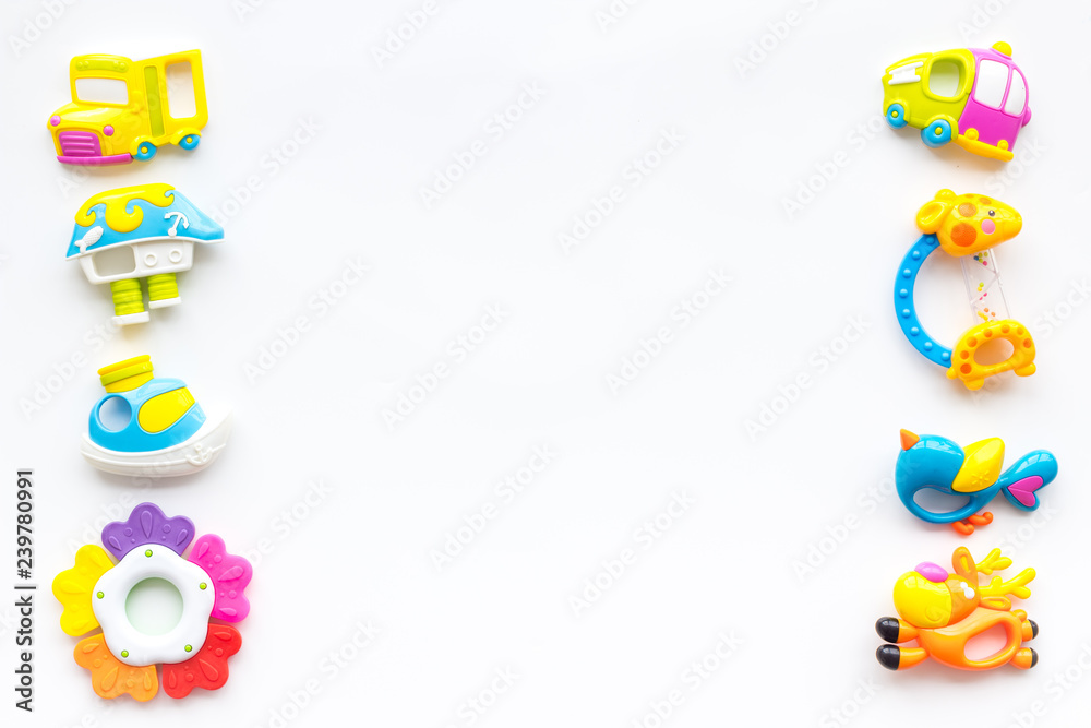 Toys for newborn baby set with plastic rattle on white background flat lay space for text Toys for newborn baby set with plastic rattle on white background flat lay space for text