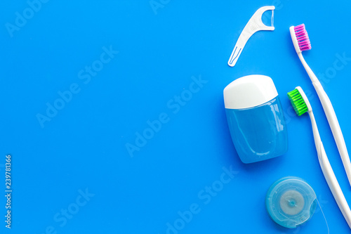 Daily oral hygiene for family. Toothbrush and dental floss on blue background top view space for text