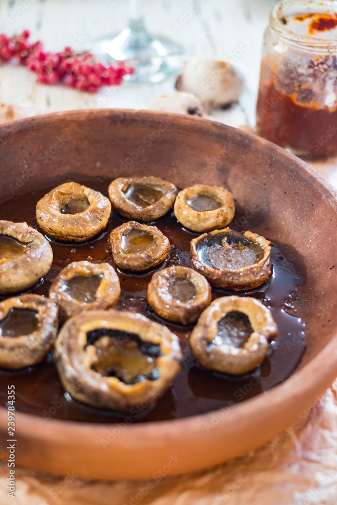 Roasted, baked mushrooms called Gryba in clay dish (ketsi - georgian traditional) with sunflower oil. Georgian traditional food.