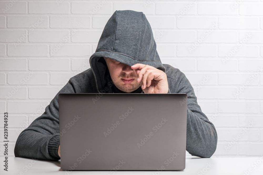 A hacker in a hood with a laptop steals data and distributes a virus A hacker in a hood with a laptop steals data and distributes a virus