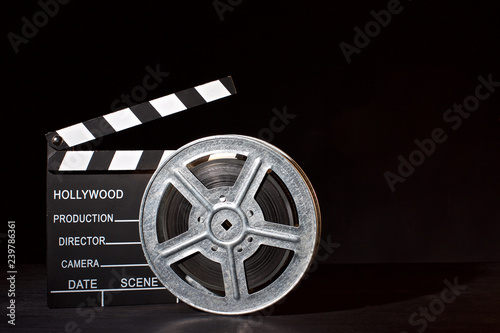 Clapperboard and film reel on the black background