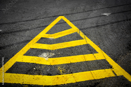 yellow triangle no parking lines painted on black asphalt road with tyre tracks