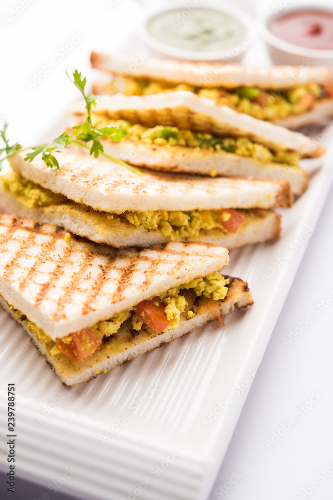 Paneer bhurji sandwich is a tasty paneer based dish made with cottage cheese.served with fresh tomato ketchup and green mint chutney. selective focus