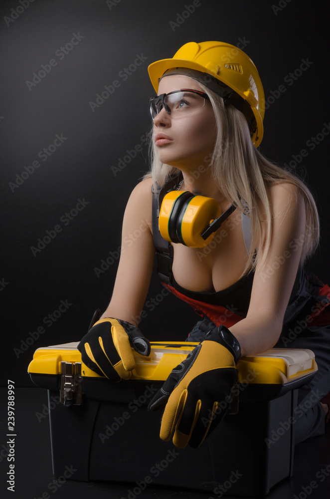 girl in overalls holding a suitcase with working tools