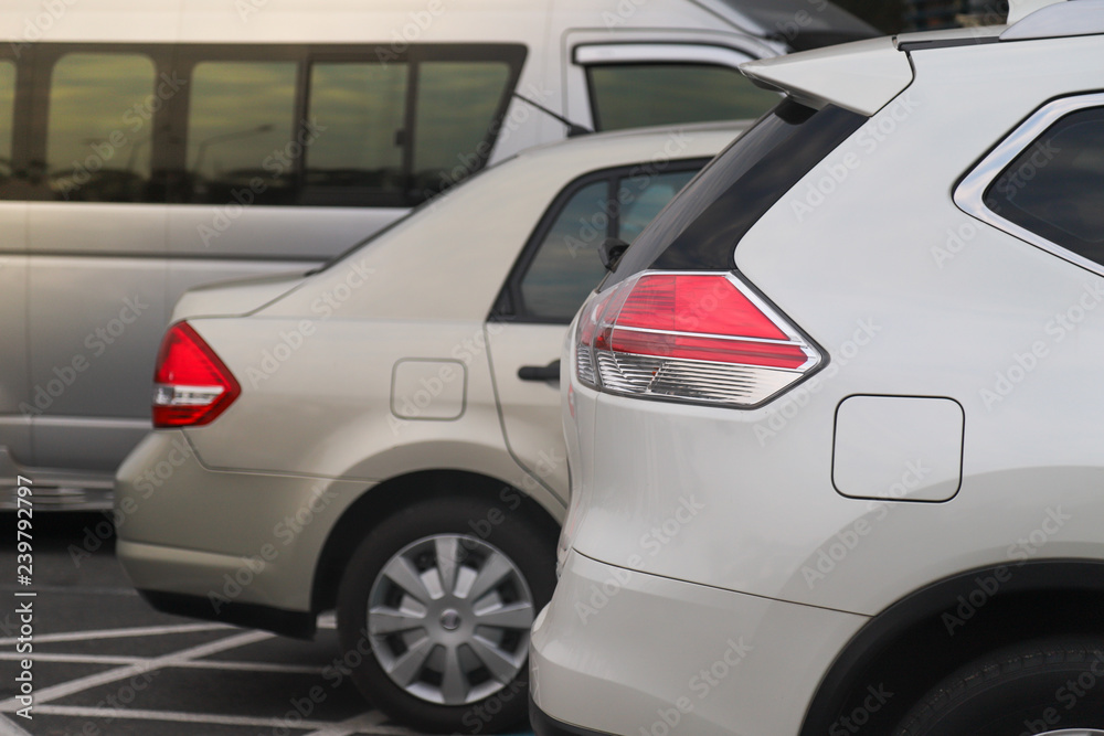 Closeup of rear side of white car parking in parking lot at twilight evening. 