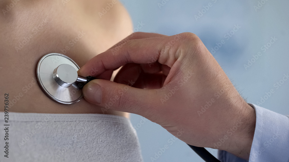 Fototapeta premium Attentive cardiologist listening to heart rate with stethoscope, health care