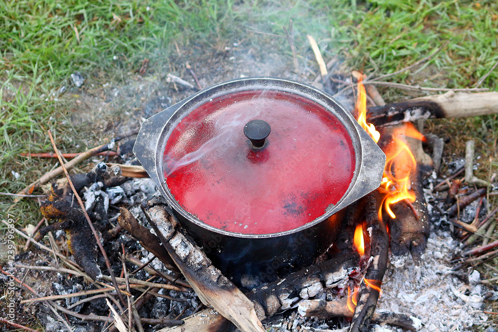Tourist bowler (cauldron) with food on bonfire, cooking in the hike, outdoor activities. Preparation food on fire. Tourist bowler (cauldron) with food on bonfire, cooking in the hike, outdoor activities. Preparation food on fire.