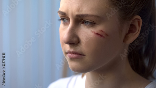 Face of upset young girl with scars on cheek, first aid after trauma, treatment