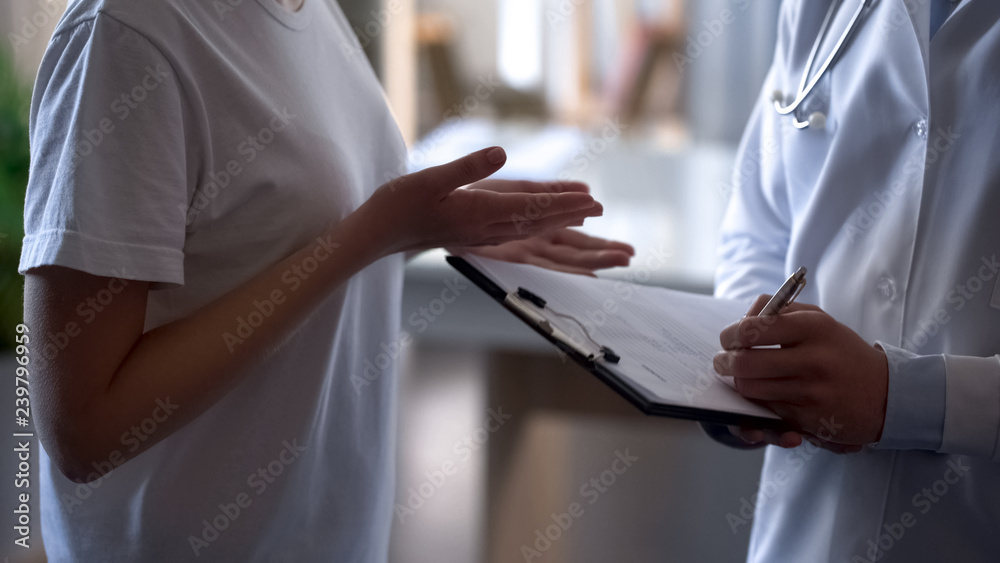Obraz premium Doctor recording patients complaints in card girl complaining of health problems