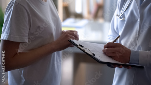 Patient on examination in clinic, doctor writing down medical records, health