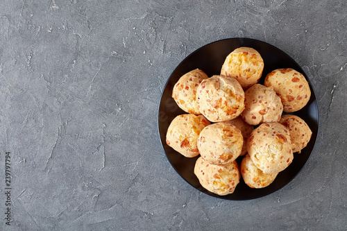 overhead view of Gougeres, cheese puffs balls on a black plate. Traditional french cheese choux buns on a concrete table, view from above, flatlay, close-up, copy space photo