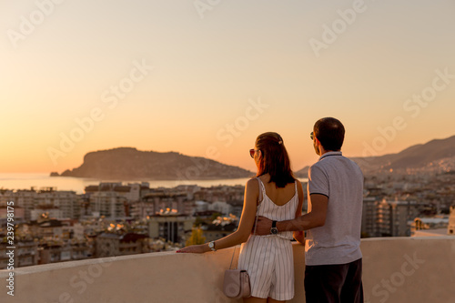Young couple watching sunset from the rooftop terrace