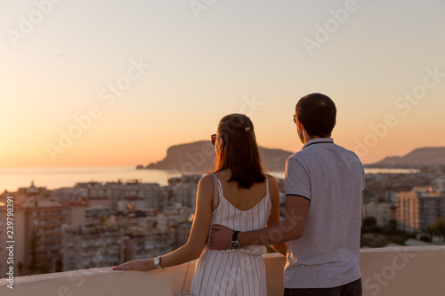 Young couple watching sunset from the rooftop terrace