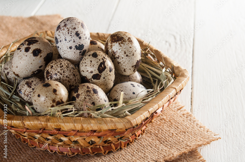 Several mottled quail eggs on straw in basket on wooden background Several mottled quail eggs on straw in basket on wooden background