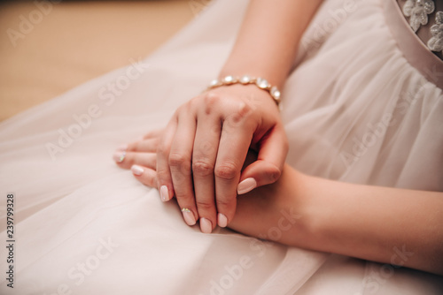 hands with a manicure lie on a wedding dress