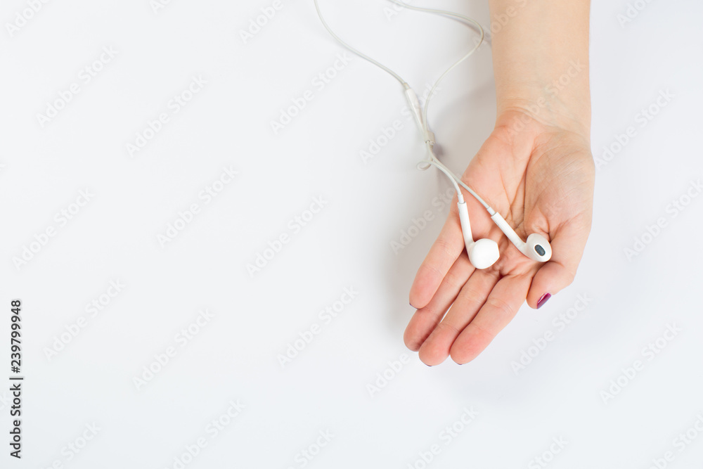 two female hands holding white headphones on an isolated white background two female hands holding white headphones on an isolated white background