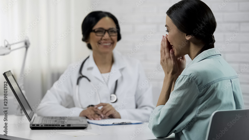 Physician informing patient about good news, showing test results on laptop Physician informing patient about good news, showing test results on laptop