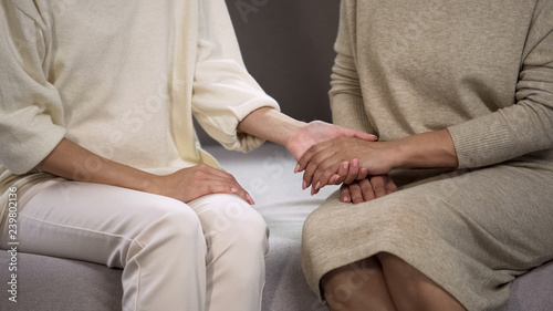 Caring daughter holding mothers hand, comforting and supporting her, relations