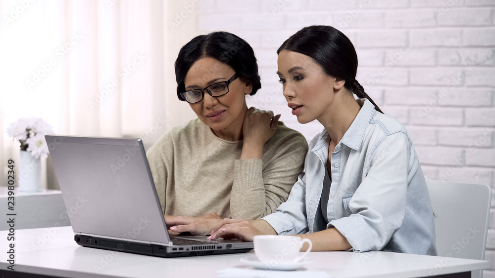 Girl teaching mother to use laptop, showing useful software, computer literacy Girl teaching mother to use laptop, showing useful software, computer literacy