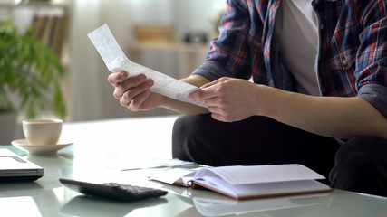 Man revising check for utilities, calculating income and expenses, family budget