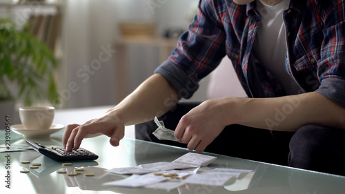 Valokuva Poor man calculating expenses, having few dollars and cents on table, debts