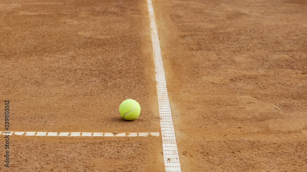 Tennis ball lying near baseline on clay court, healthy lifestyle, close up