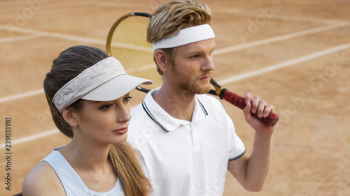 Motivated female and male tennis players looking at scoreboard, success in sport © motortion