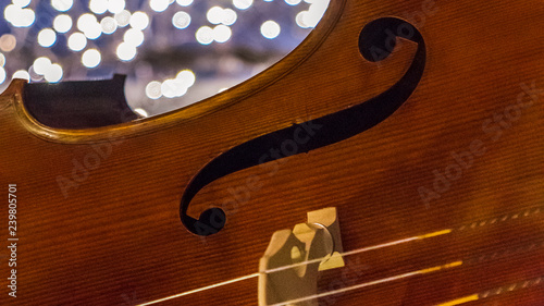 Close up of a cello, Christmas lights and glitters are in the background.