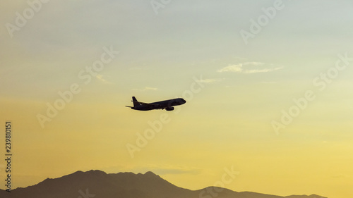 silhouette of an airplane flying over the mountains against a clear sky . Copy space fot text