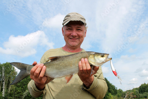 man fisherman holding a big fish and smiling