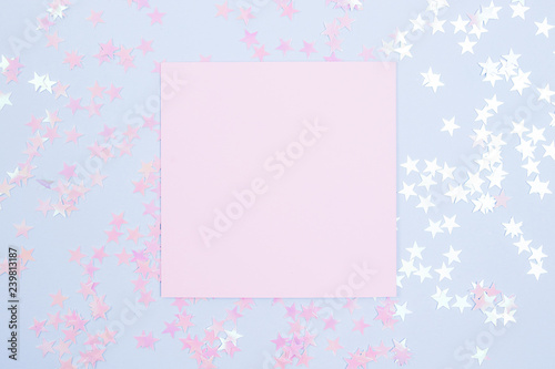 Frame of glitter stars with pink blank card mockup on blue background. Flat lay. © Struzhkova Ilona
