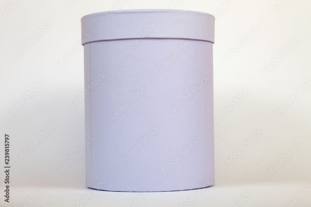 A purple cardboard box of a tube close up on a white background of a round shape with a closed lid for gift wrapping or storing flowers, a surprise, or a package in shopping stores upon purchase. A purple cardboard box of a tube close up on a white background of a round shape with a closed lid for gift wrapping or storing flowers, a surprise, or a package in shopping stores upon purchase.