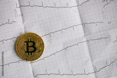 Bitcoin is alive. The gold coin lies on a paper photo