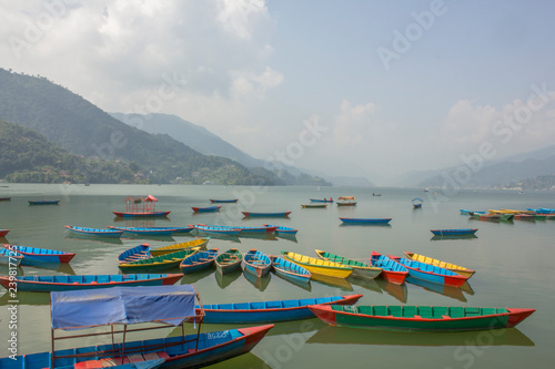 a lot of wooden colored boats on the lake in the daytime against the backdrop of the mountains