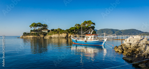 Blue boat parked in the Laganas dock with the Cameo island in the back