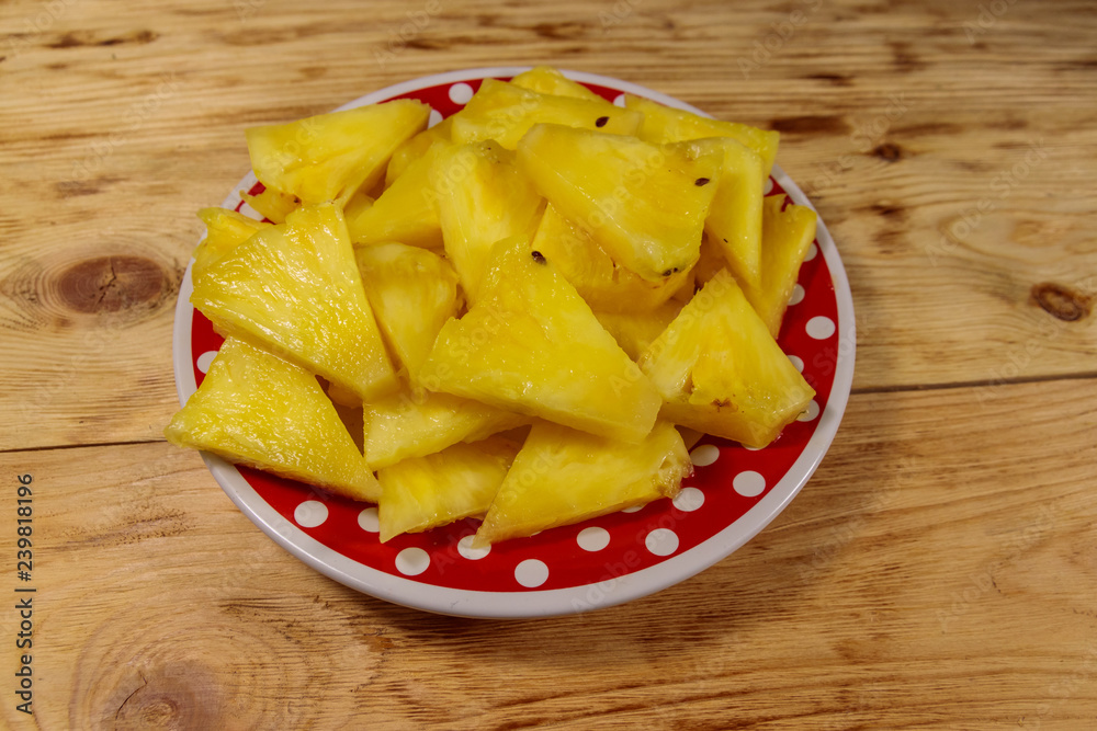 Pieces of pineapple in a plate on wooden table Pieces of pineapple in a plate on wooden table