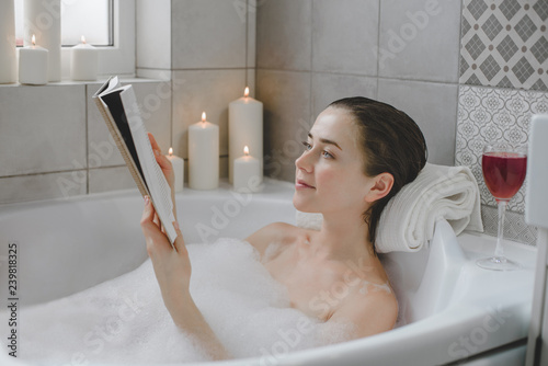 Young woman relaxes in a hot bath full of foam.