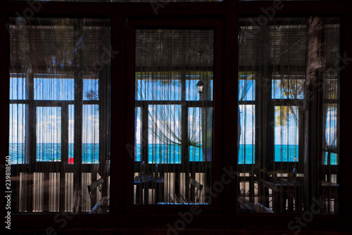 Through the window you can see the cafe s atmosphere and the blue and turquoise sea and sky.