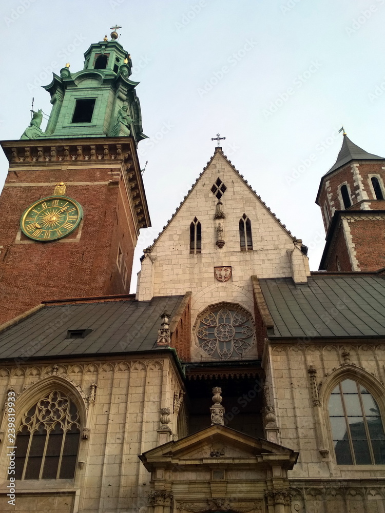 The view of the pilgrim from below on the beauty, uniqueness and greatness of the medieval Catholic churches in Krakow against the background of the cloudy blue winter sky.