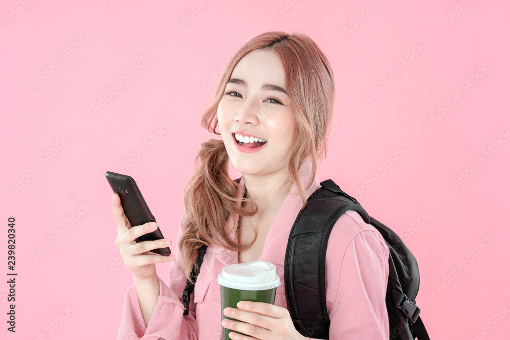 Asian woman tourist use smartphone for online shopping, jeans jacket clothing with backpack, pink background Asian woman tourist use smartphone for online shopping, jeans jacket clothing with backpack, pink background