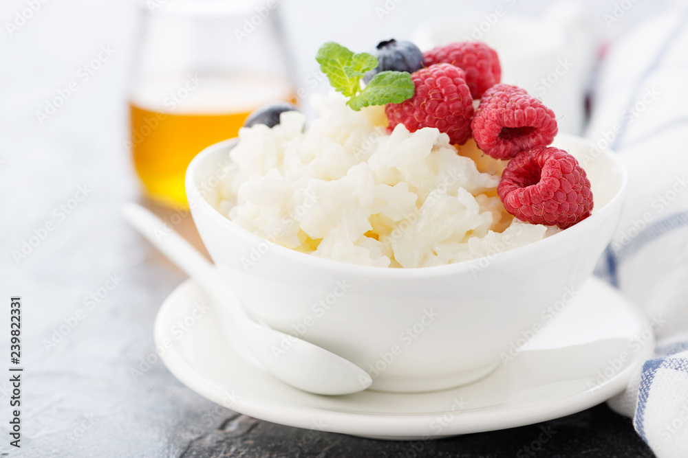 Rice porridge or pudding with fresh raspberry in a white bowl for a breakfast. Rice porridge or pudding with fresh raspberry in a white bowl for a breakfast.