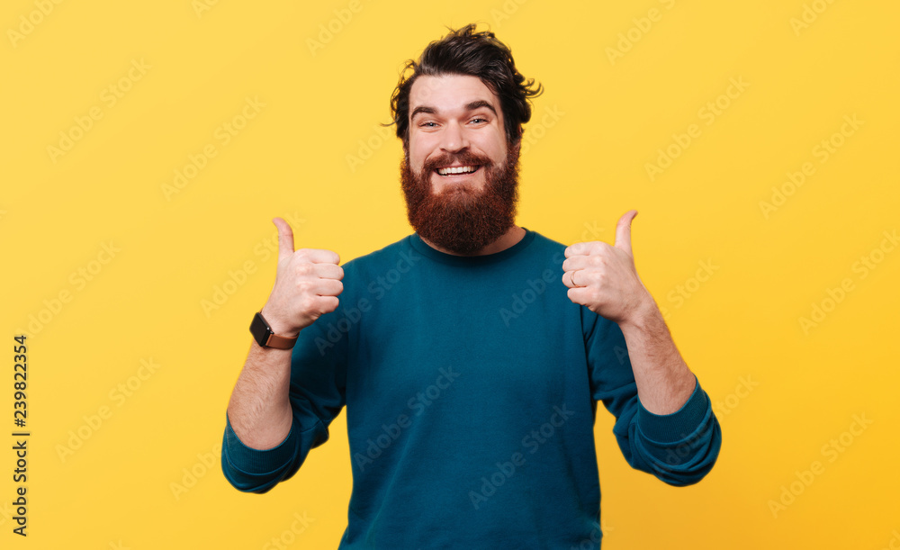Portrait of happy man showing thumbs up over yellow background Portrait of happy man showing thumbs up over yellow background