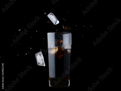 Ice cubes splashing into cola isolated on black