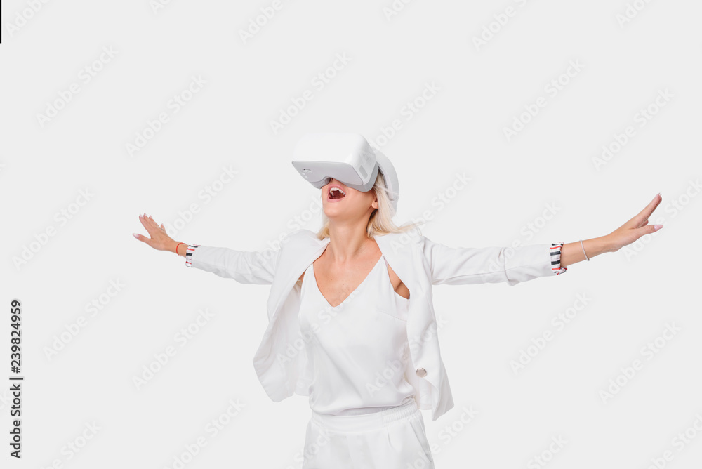 Blond woman in white suite with virtual reality goggles. Studio shot on white background Blond woman in white suite with virtual reality goggles. Studio shot on white background