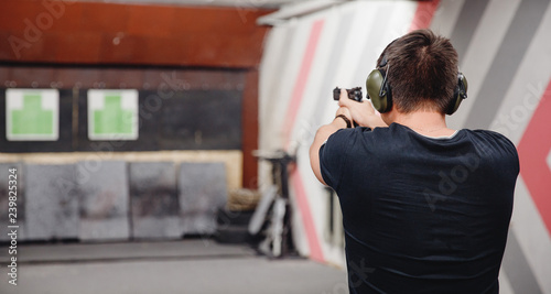 Man directs firearm gun pistol at target firing range or shooting range photo