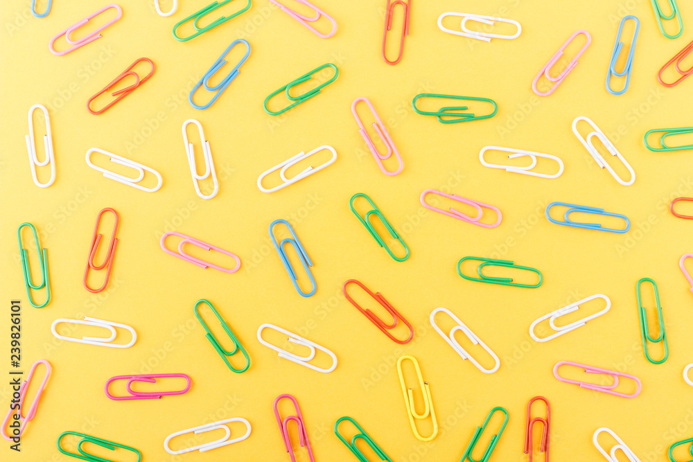 Background made from colored paper clips on the orange base Background made from colored paper clips on the orange base