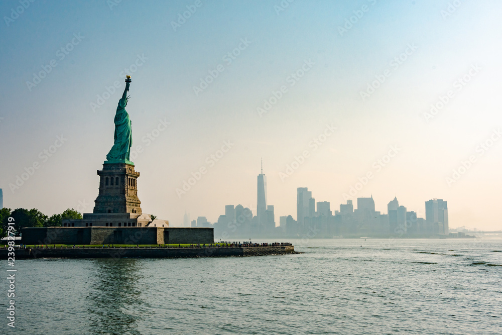 Liberty statue in New York City with skyline of the island of Manhattan