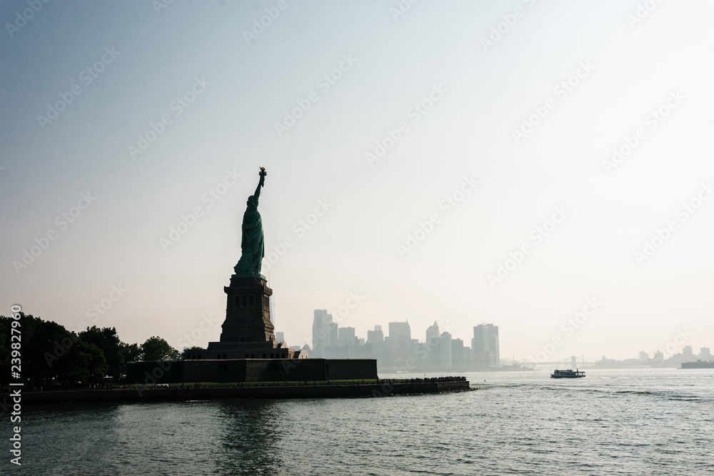 Liberty statue in New York City with skyline of the island of Manhattan