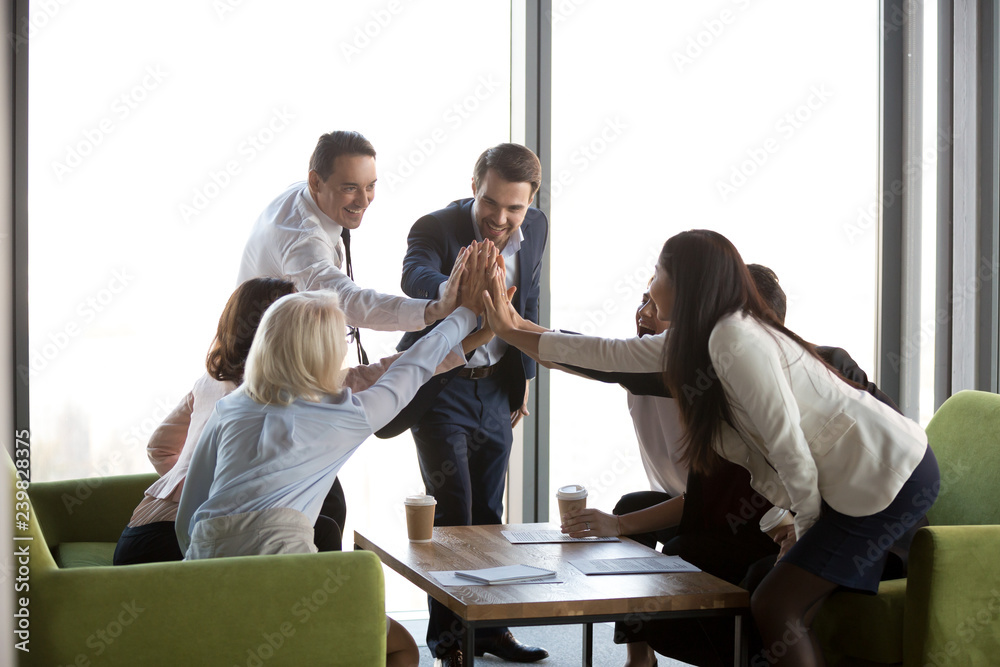 Diverse businesswomen businessmen company members reached goal having success at work gathered after negotiations together for celebrating. Businesspeople giving high five show team spirit and support