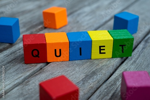 colored wooden cubes with letters. the word quiet is displayed, abstract illustration